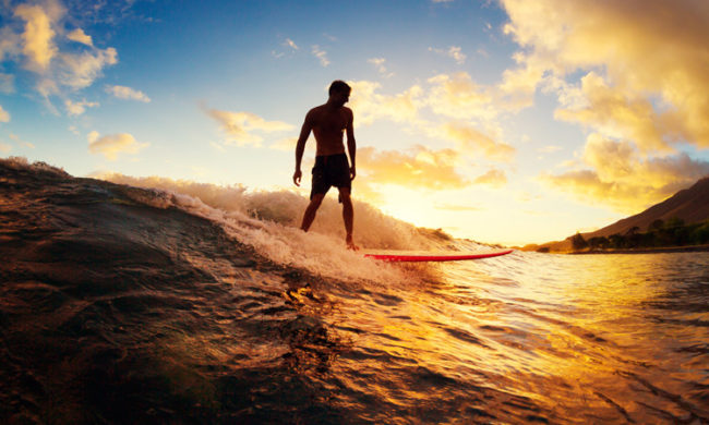 Surfing at Sunset. Young Man Riding Wave at Sunset. Outdoor Acti